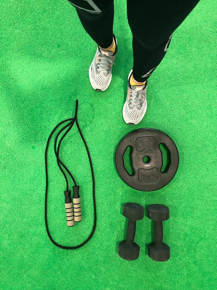 Crafting Captivating Headlines: Your awesome post title goes here Flat lay of dumbbells, weight plate, and skipping rope on a green gym floor.